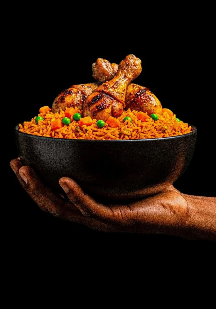 A black bowl of jollof rice with grilled chicken, held in two hands